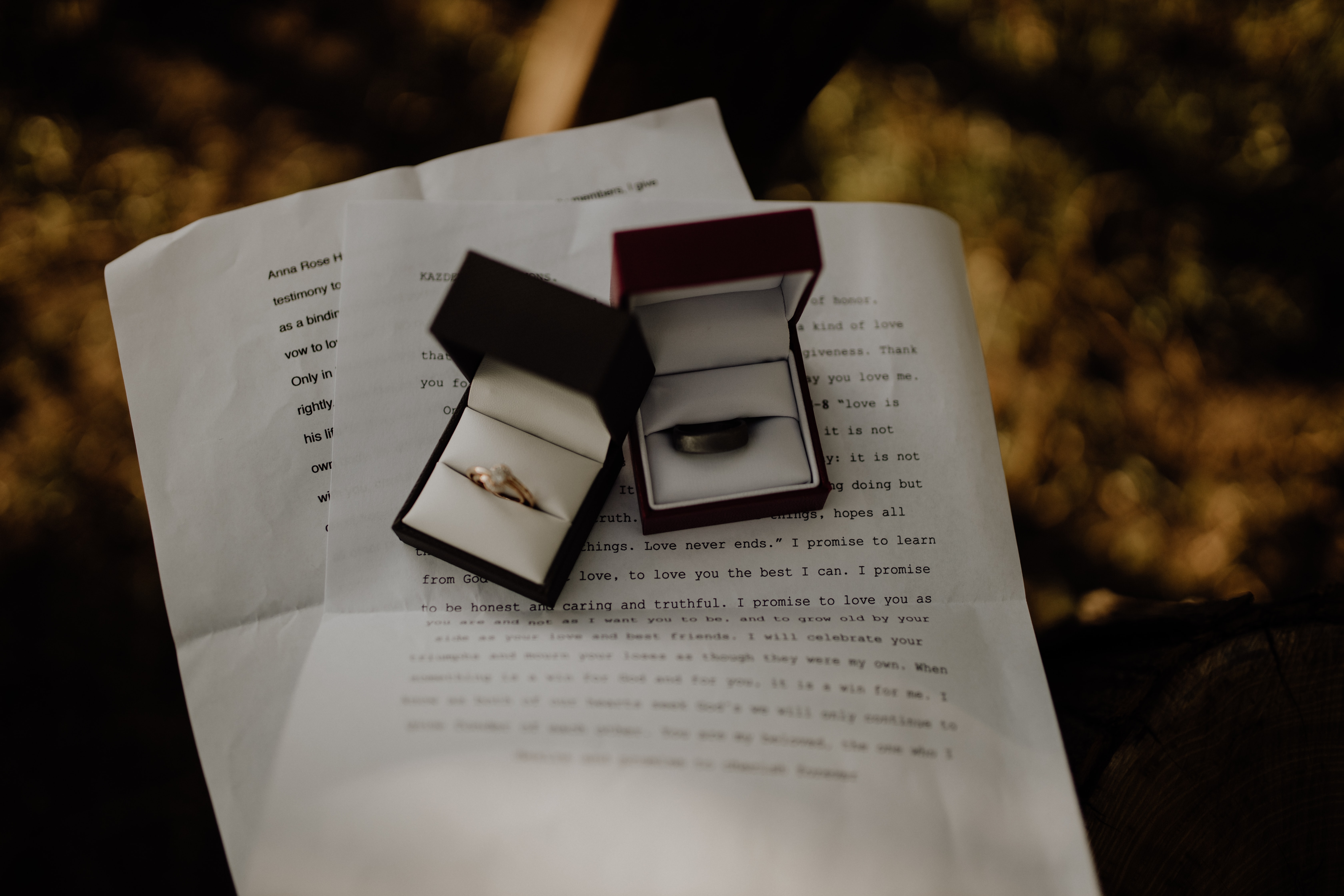 Two boxes with wedding rings sitting on sheets of paper with typed text